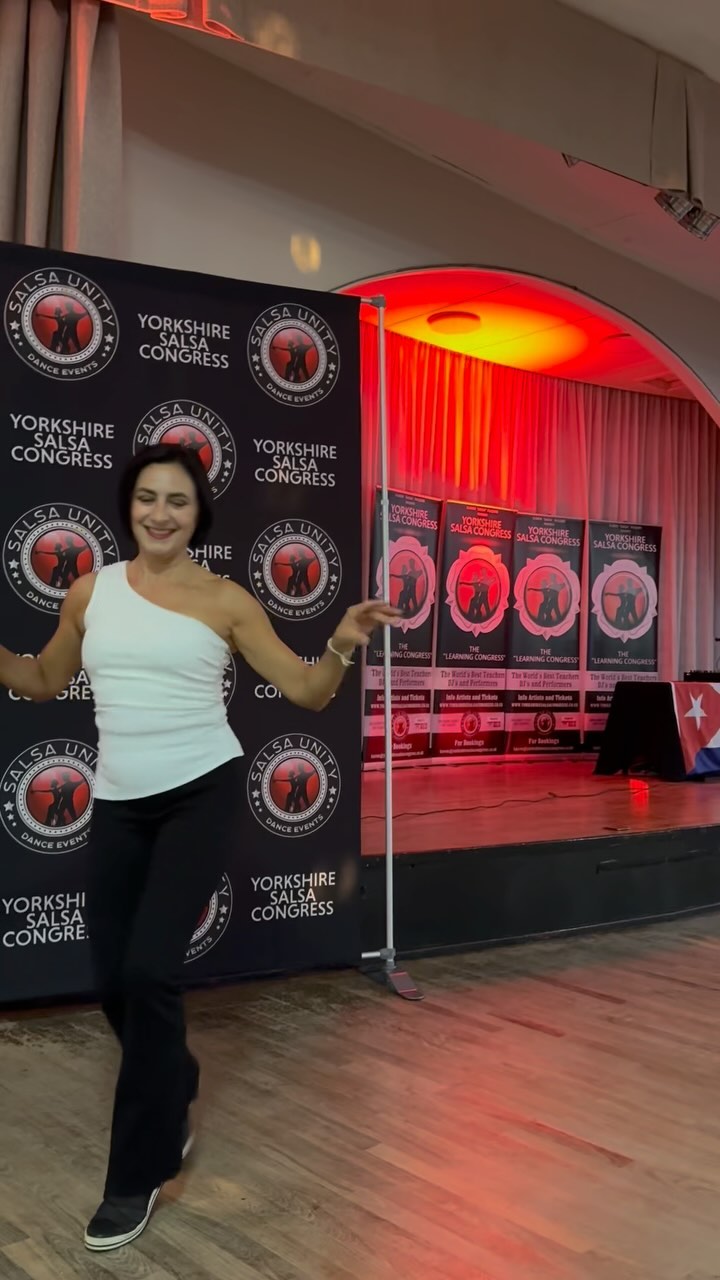 Karen Salsa McQuire dancing in front of the Salsa Unity and Yorkshire Salsa Congress banners